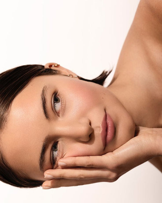 Young Asian woman with glowing skin touching her face, showcasing results from Korean skincare routine