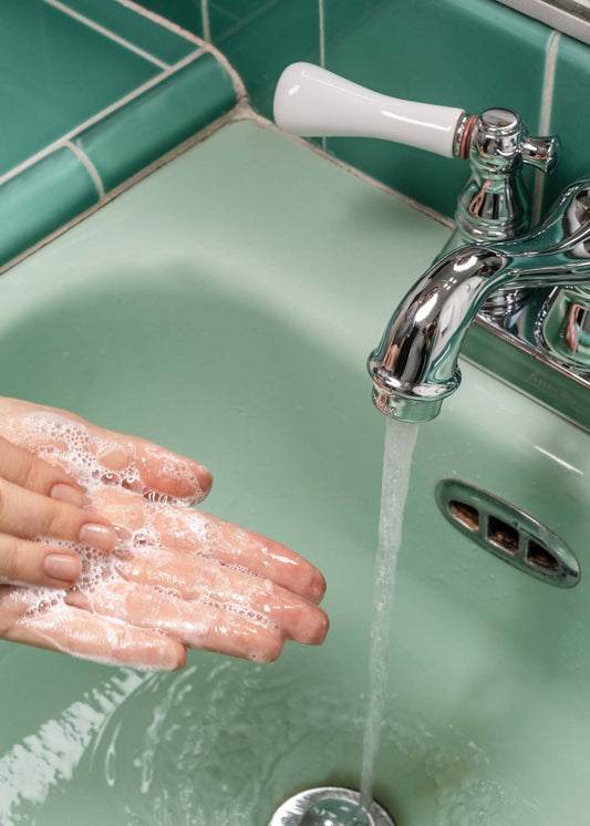 Person lathering cleaner in hand near sink