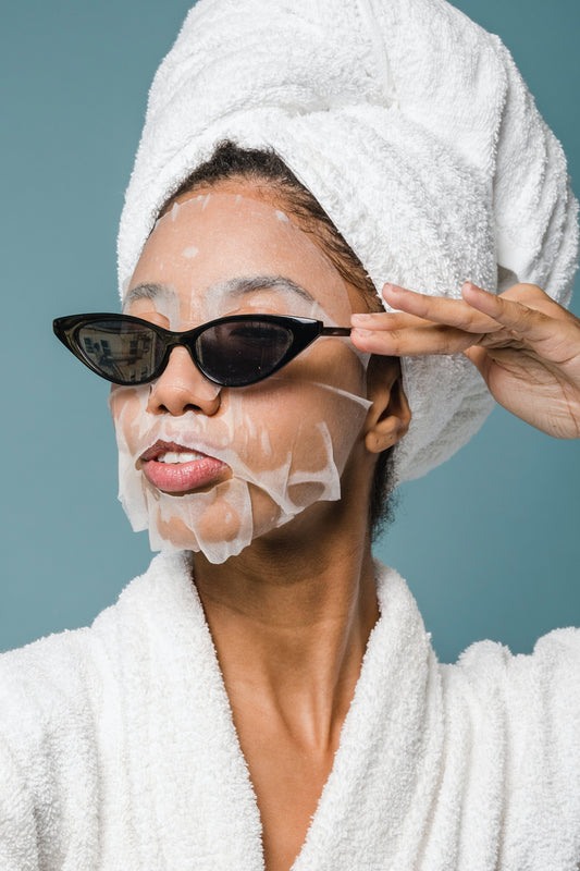 Women with skincare face mask posing with sunglasses in house coat